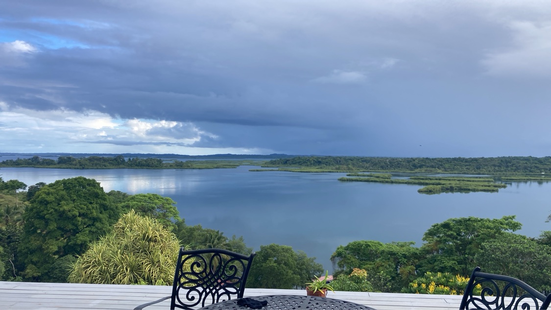 The view from the Toucan Bay balcony — chairs on the deck looking out over the lagoon and jungle islands under a moody sky in Bocas del Toro